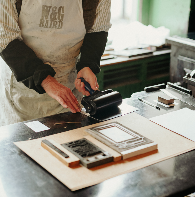 A man printing in the Bairds Print Shop at the Folk Museum 