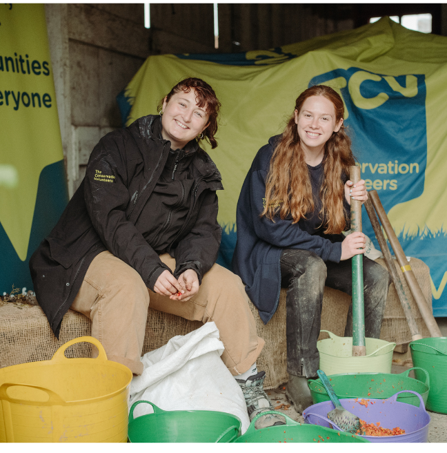 Two women smiling while potting soil into pots