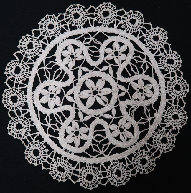 A lace doily. The pattern is intricate, making use of circles on the edges and a sort of rounded flower design in the middle.