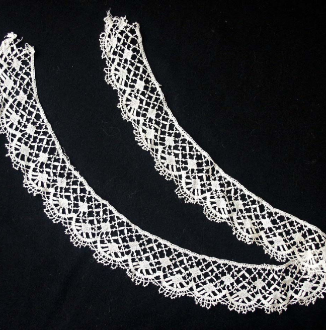 A trim of bobbin lace. The pattern uses diamond shapes, with loops of lace at the edges. 