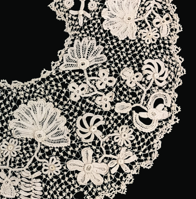 A close up look at crochet lace with knots worked into the lace grid and flower patterns. 