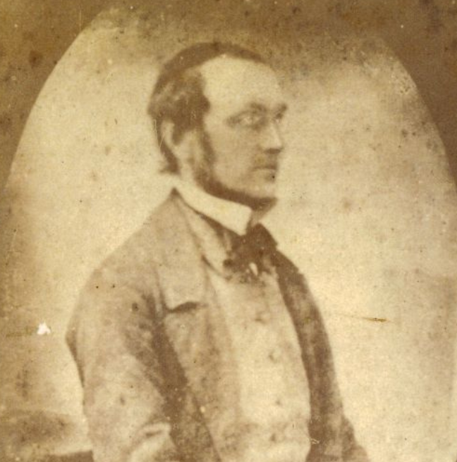 An old black and white photograph of a man. His dress is formal and he stares off to the right. 