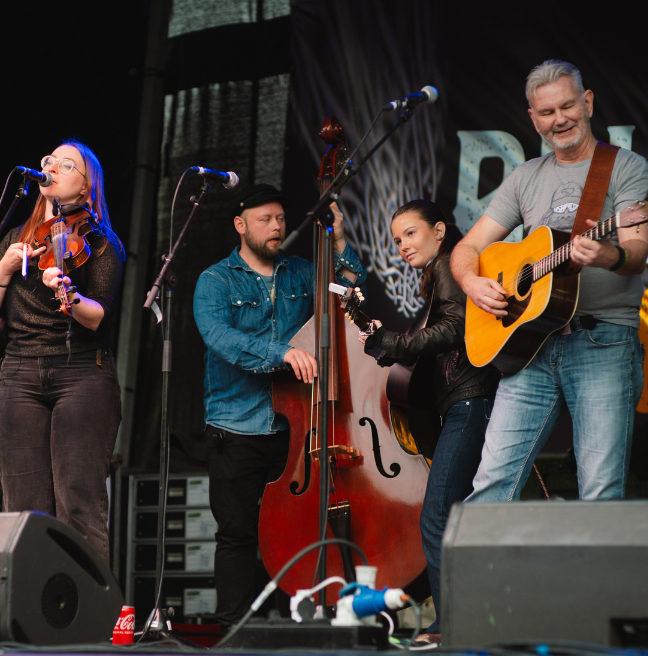 A 4 piece band on stage playing a double bass, violin and guitar 