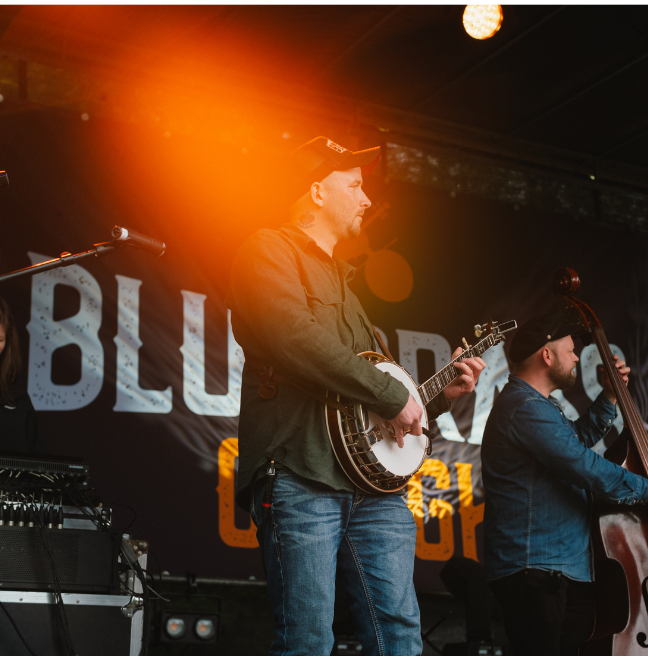 A man playing a banjo on stage at bluegrass omagh