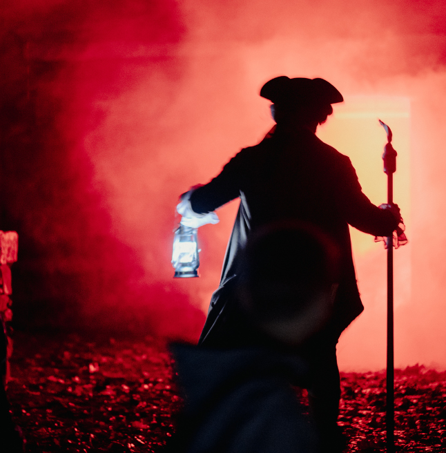 A man dressed in costume holding a torchlight