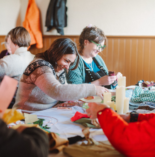 two women smiling while making a rag wreath