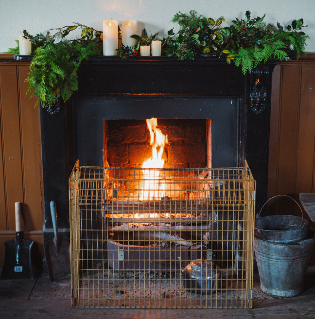 a fireplace at ulster folk museum dressed with a green garland