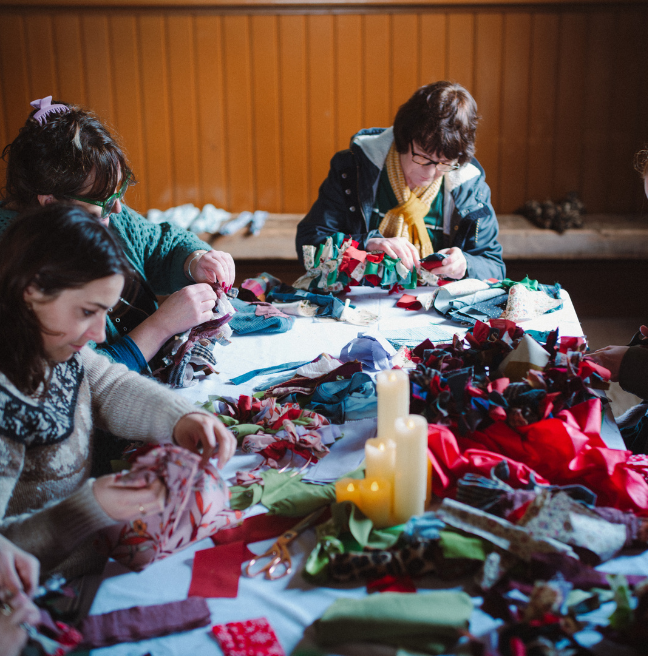 women around a table making rag wreaths