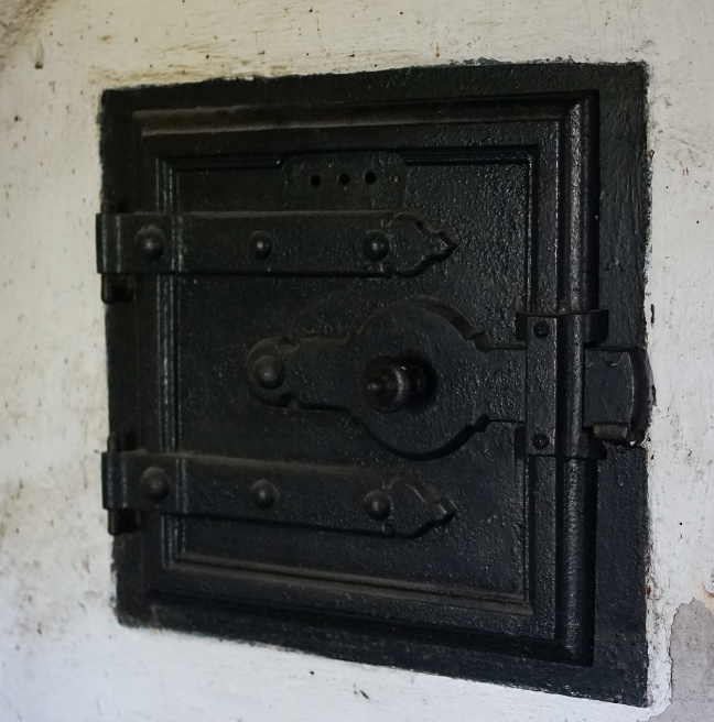 An oven set deeply into the wall is seen with its door closed.