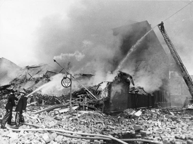 Image of two firemen dousing the smoking wreckage of Printing Works in Union Street Belfast after its destruction in a bomb attack. 