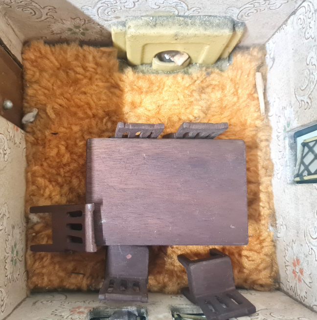 The dining room of a dolls' house, with a table and chairs and a fireplace.