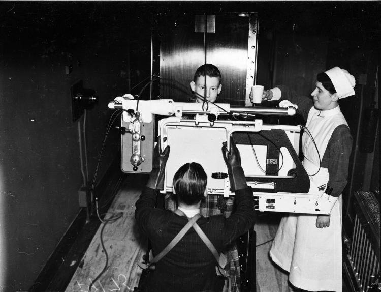 A nurse assists a doctor in demonstrating an x-ray machine.