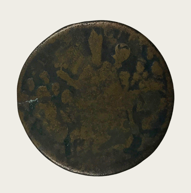 An old, worn coin. An image of St. Patrick holding a three leaf clover is just visible.