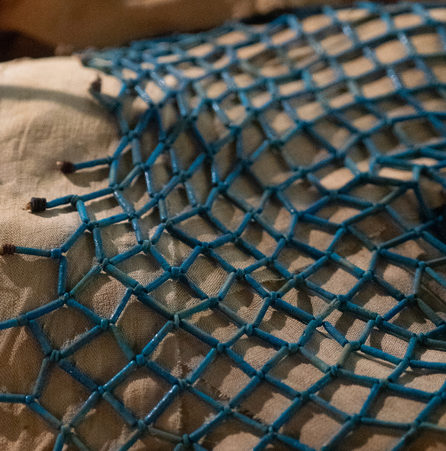 A cape made of blue beads in a netting.