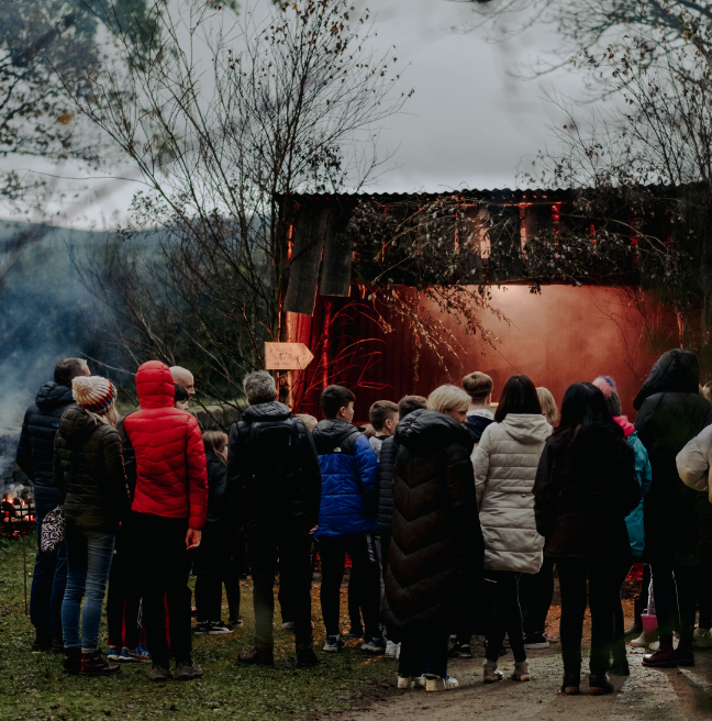 A group of people at dusk looking into a house/stage area