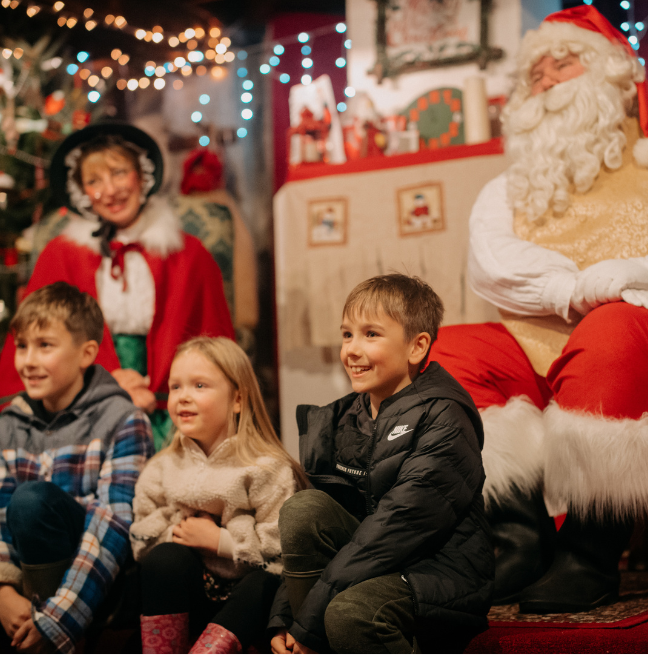 A group of small children visiting Father Christmas and Mrs Claus