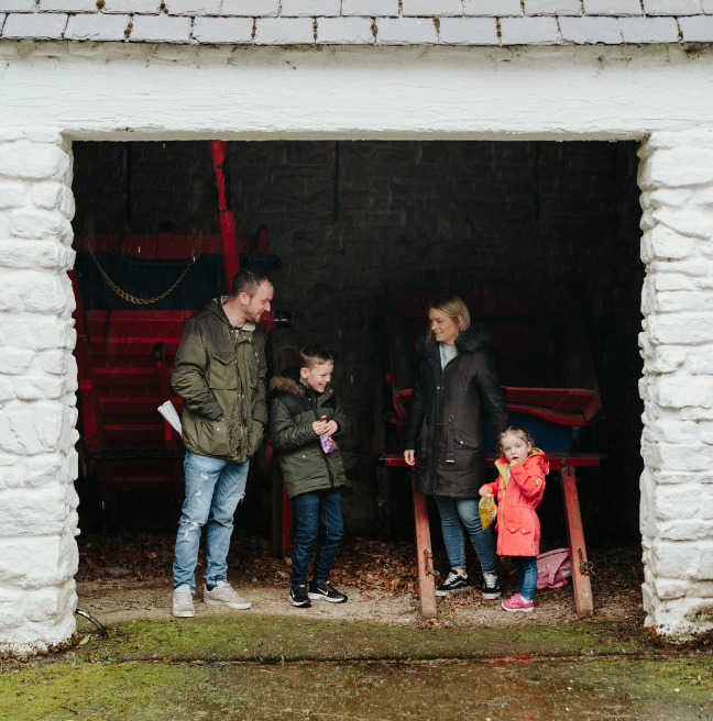 A family of four in front of a building at the folk park - a man, a young boy, a woman and a young girl