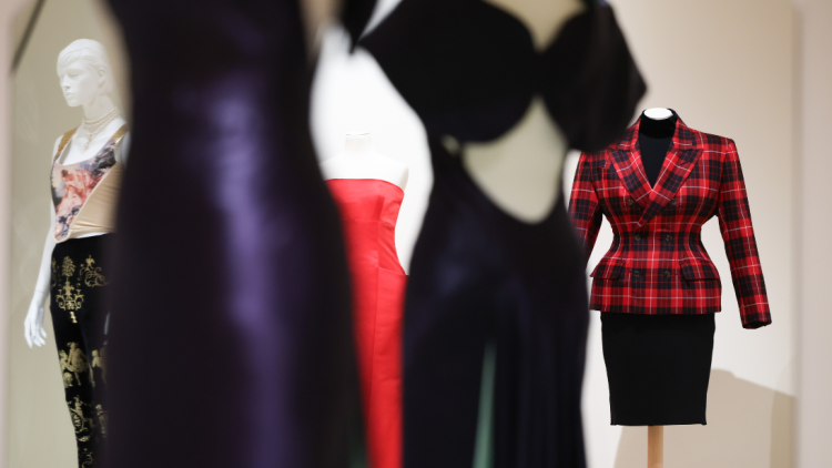 Colourful garments on white mannequins in a cream painted room.