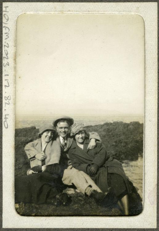 Small photograph of a man and two women sitting on a rock