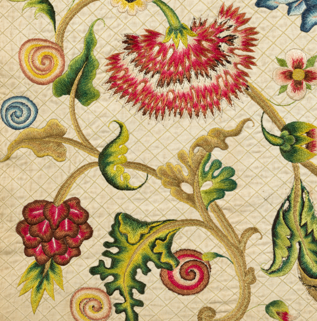 A detailed image of the Lennox Quilt showing large red flowers, a swirly red berry, and other swirly circles, and leaves and stems.