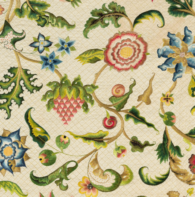 A detailed image of the Lennox Quilt showing an embroidered strawberry, flowers of red and blue, a little red berry, and lots of leaves and small flowers of blue red and yellow.