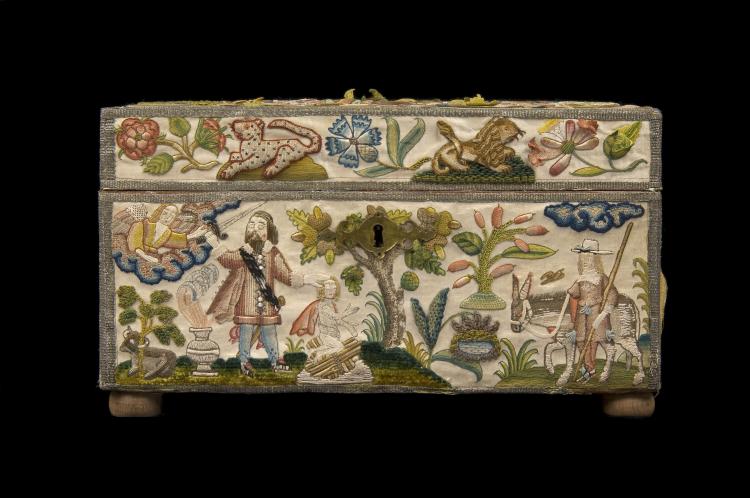 The front of an intricately embroidered box, with a key hole. The lid shows two animals, a lion and perhaps a cheetah, with blue and pink flowers. The bottom shows an angel handing a sword to a man, who stands with his hand on the head of a young child or cherub. On the right a man guides a donkey.