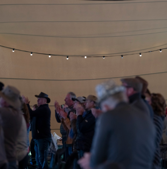 a crowd of people in a stretch tent clapping and enjoying music at a concert