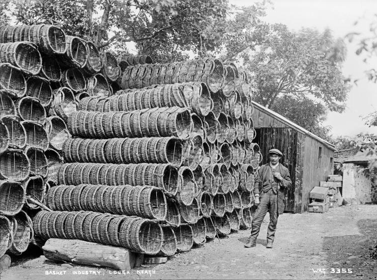 A black and white photograph of many woven baskets piled up in a pyramid.
