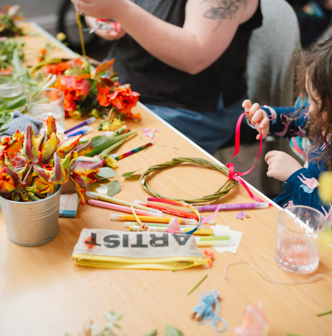 A child making a flower crown at a brown table