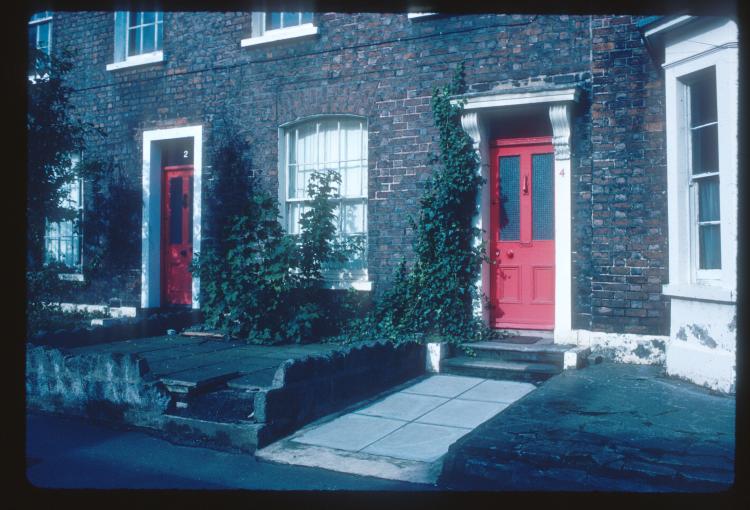 A colour image of a the facade of a building in south Belfast. The front door is red.