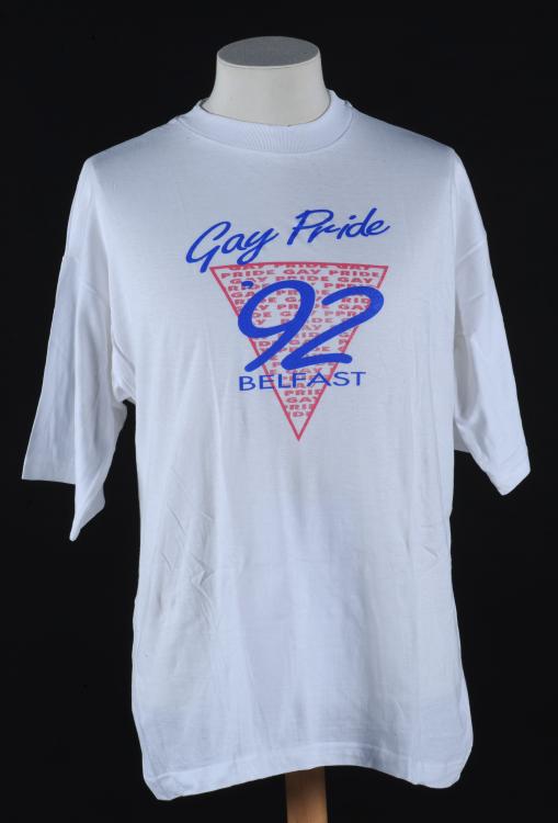 A white tshirt made for the second pride in Belfast. The logo is an inverted pink triangle with ''92' written in it.