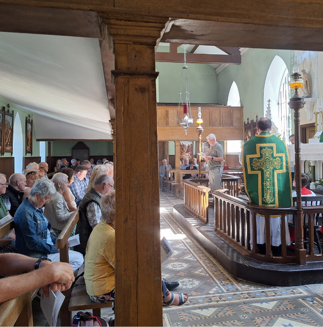 A man stands at the altar of a Catholic Church, giving a reading.