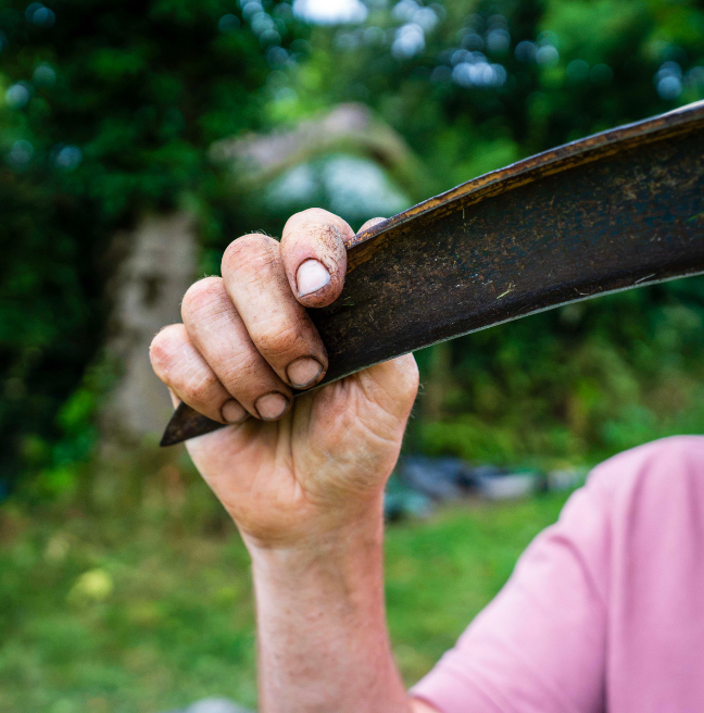 A mans hand holding the end of a scythe 