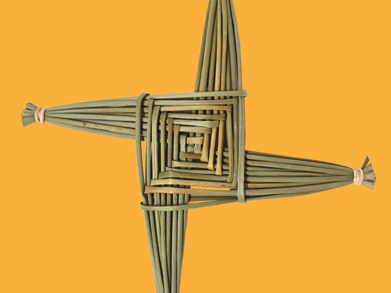 A golden and green St Brigid's cross on a bright orange background.