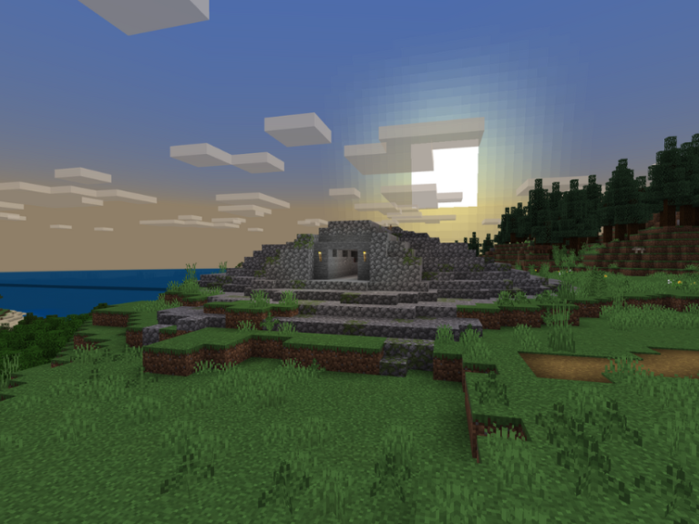 A Minecraft scene showing grass and a tomb with sea and sky on the horizon.