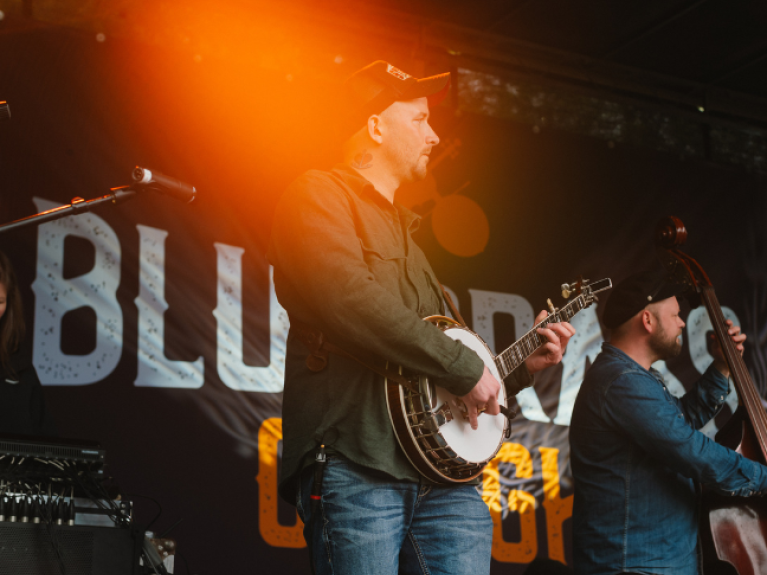 A man playing a banjo on stage at bluegrass omagh