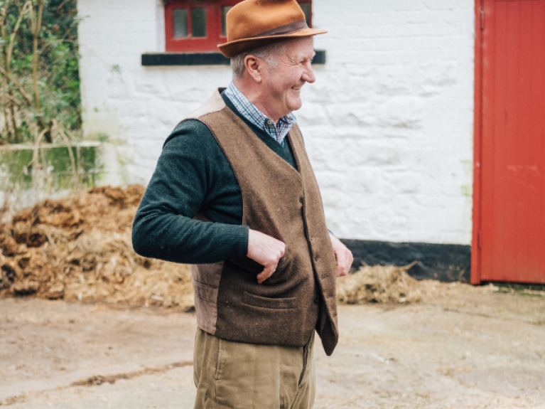 A man who is a farmer standing outside a farmhouse in ulster folk museum