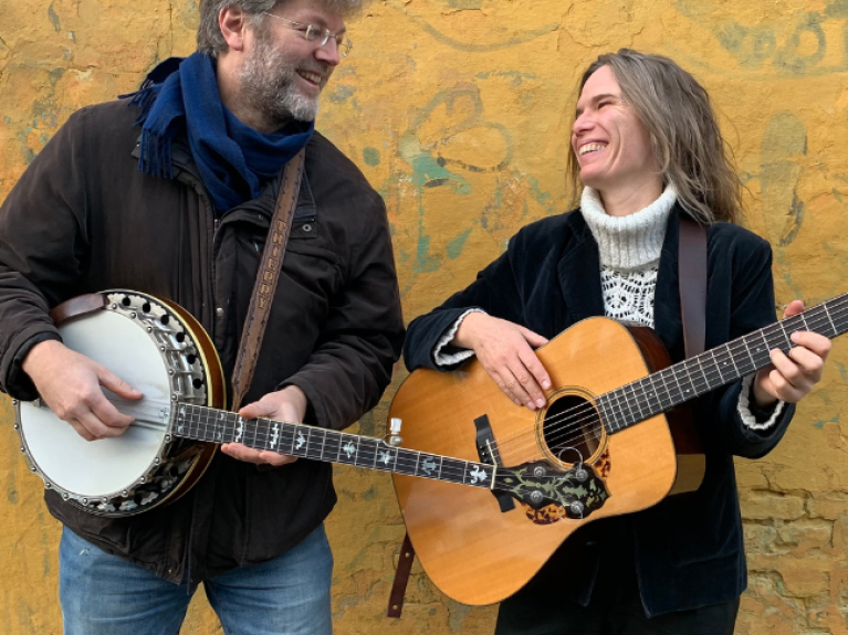 A man with a banjo and a woman with a guitar who are the band called table for two 