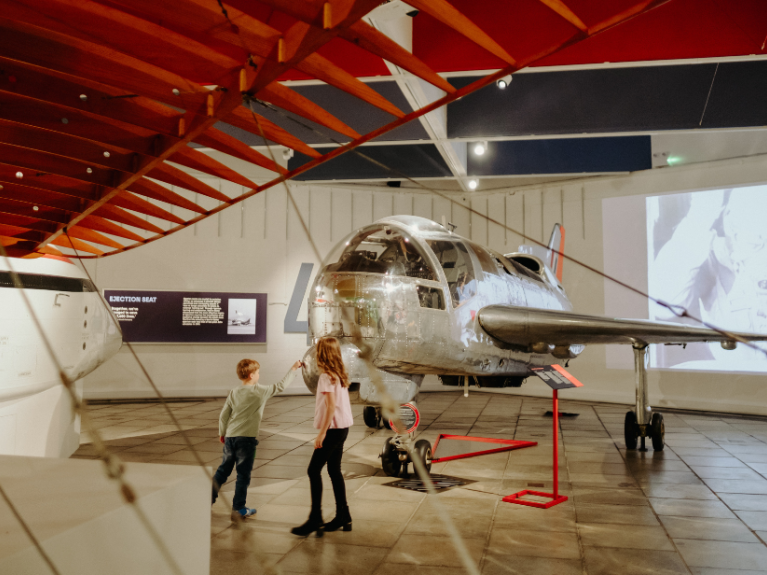 Two children playing beside a historic plane on display at transport museum