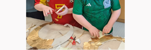 two boys creating a gold lunlae with paper and crafts