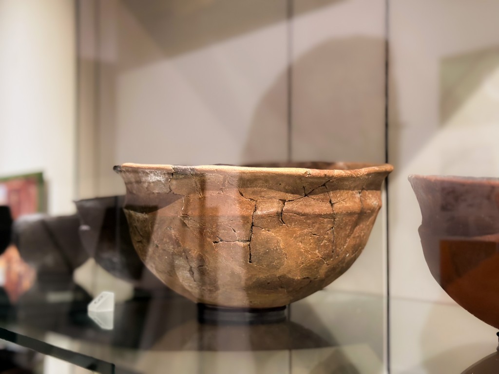 An old clay pot behind a glass case.