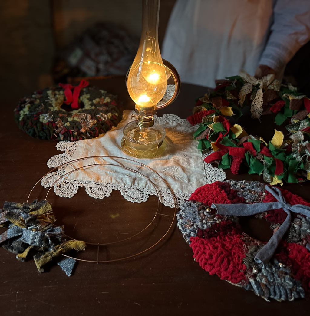 A table of rag wreaths with a lamp illuminating the cottage.
