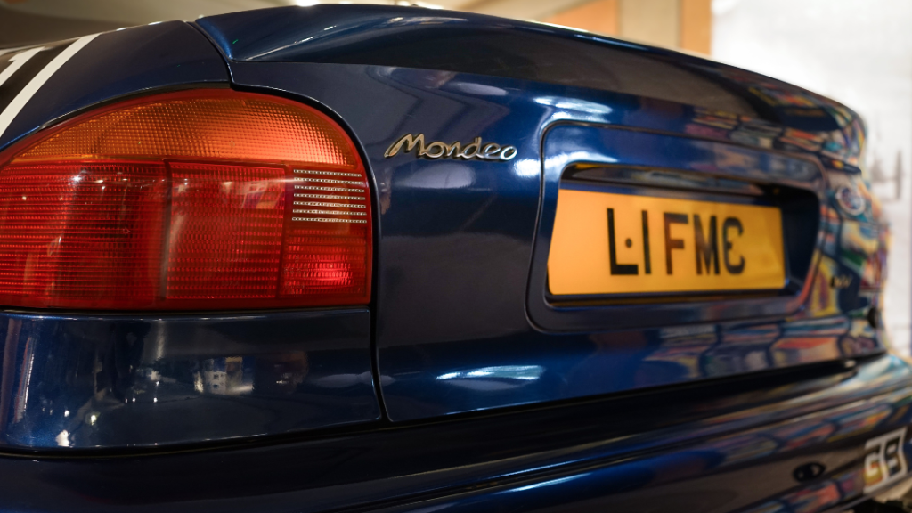 The rear of a blue Ford car. There is a metal embossment reading 'Mondeo'. 