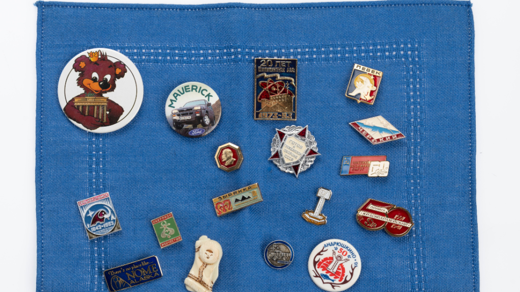 A blue towel has been used to hold 17 badges, all related to travelling across Europe, Russia, and North America.