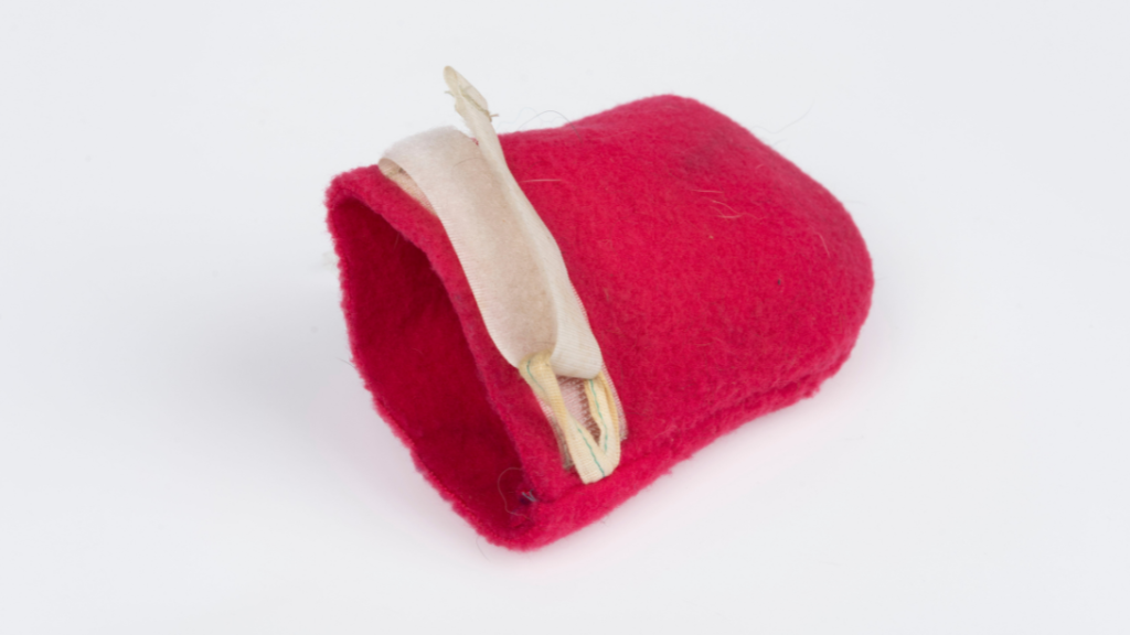 A red bootie for the paw of a dog who will be travelling over snow and ice. A white tie is at the top to keep it in place. 
