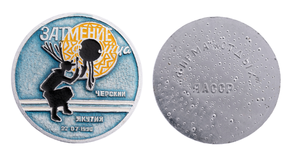 A coin commemorating the solar eclipse of July 1990. The design features the silhouette of a man wearing antlers; he is playing a drum, which is also the moon in front of the sun in the design. On the back marks the name of the producing company with letters denoting the Yakut Autonomous Soviet Socialist Republic.