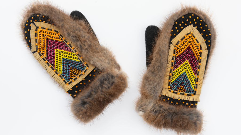 A pair of fur gloves with intricate beading on the back of the hands.