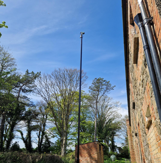 A tall pole supports a laser than scares away birds from thatched roofs.