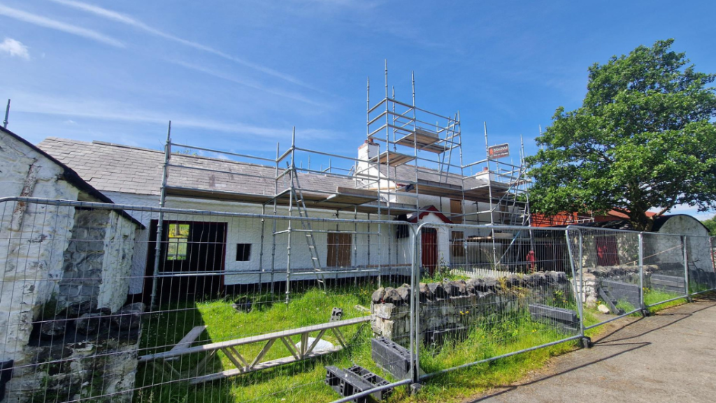 A large farmhouse is covered in scaffolding.