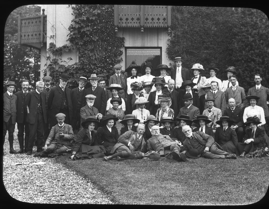 A group of people dressed in early 19th century fashion pose on a lawn for a photograph.